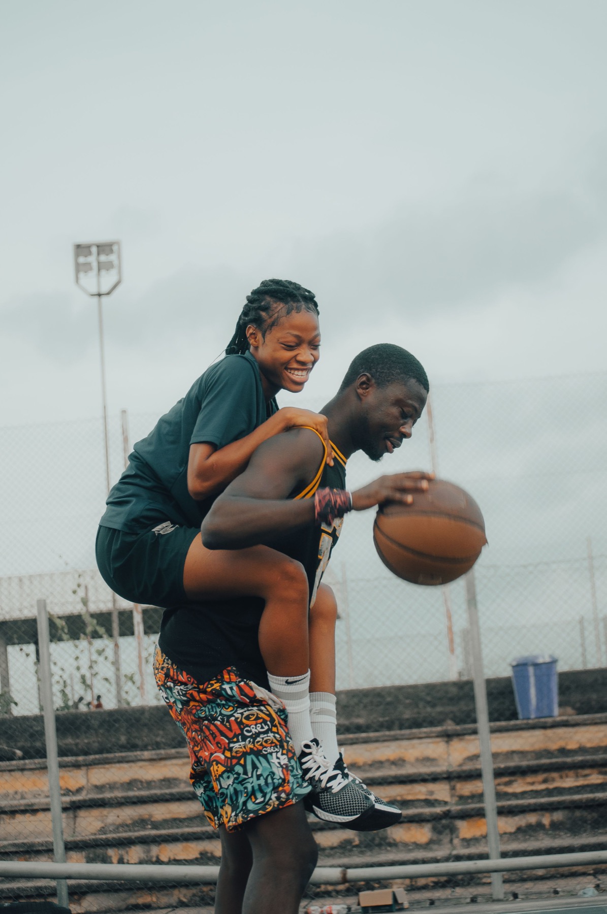 A playful couple laughing on a basketball court